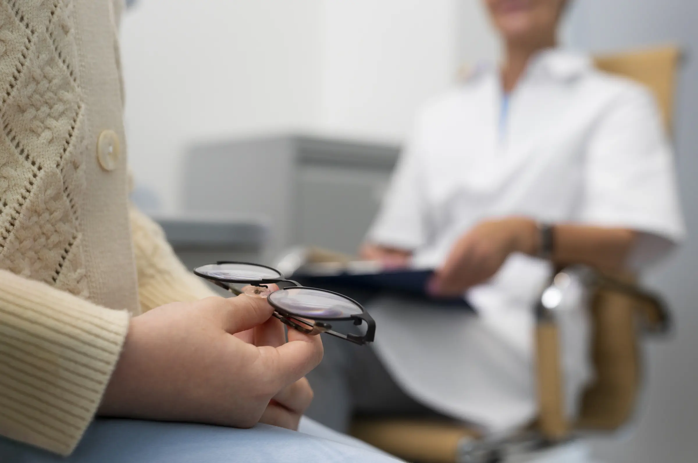 Nahaufnahme: Kundin hält ihre Brille im Gespräch mit dem Optiker - Symbolbild für die Aufklärungssituation vor dem Sehtest
