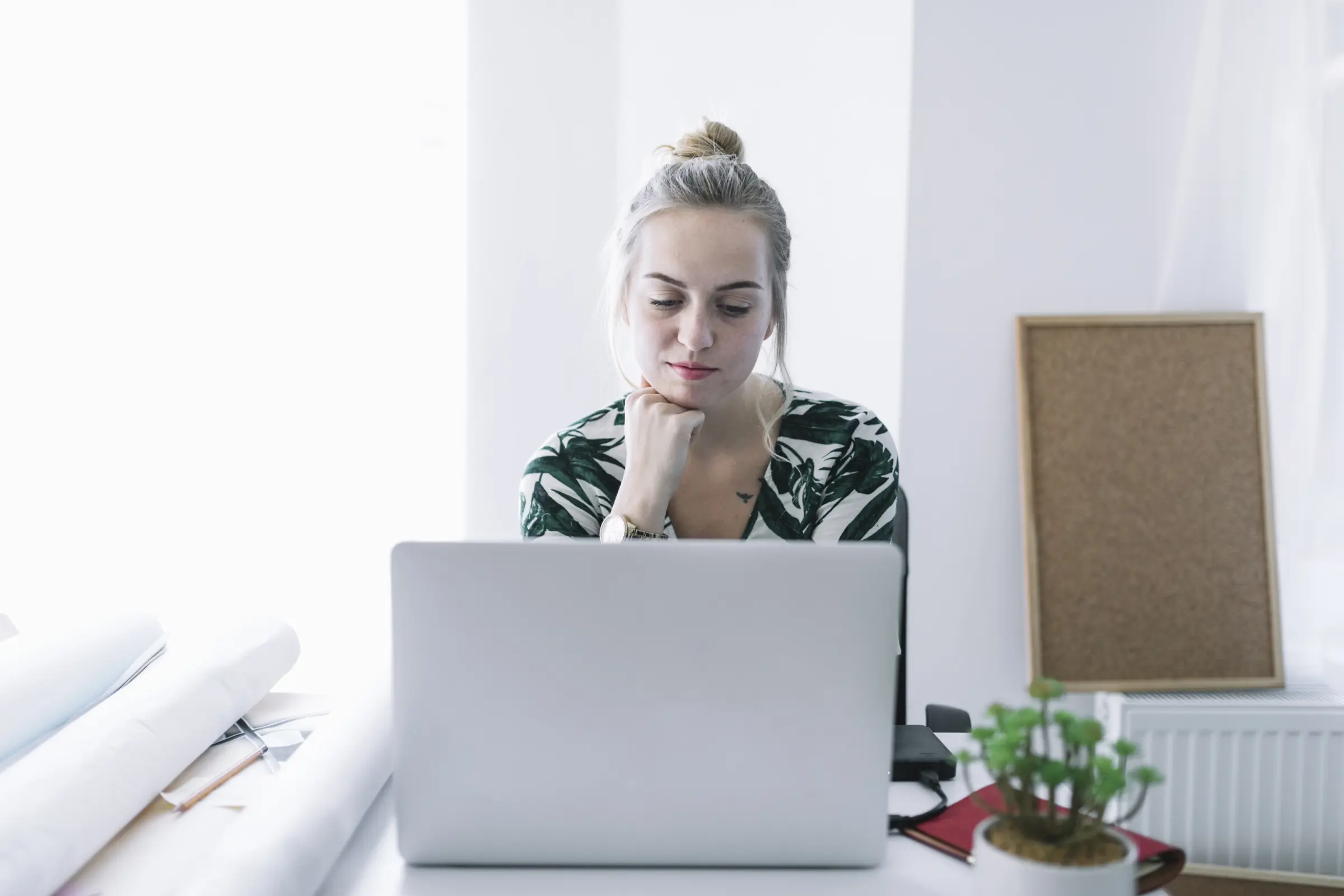 Junge Frau sitzt konzentriert vor dem Laptop – Symbolbild für einen Online-Sehtest von zu Hause aus.