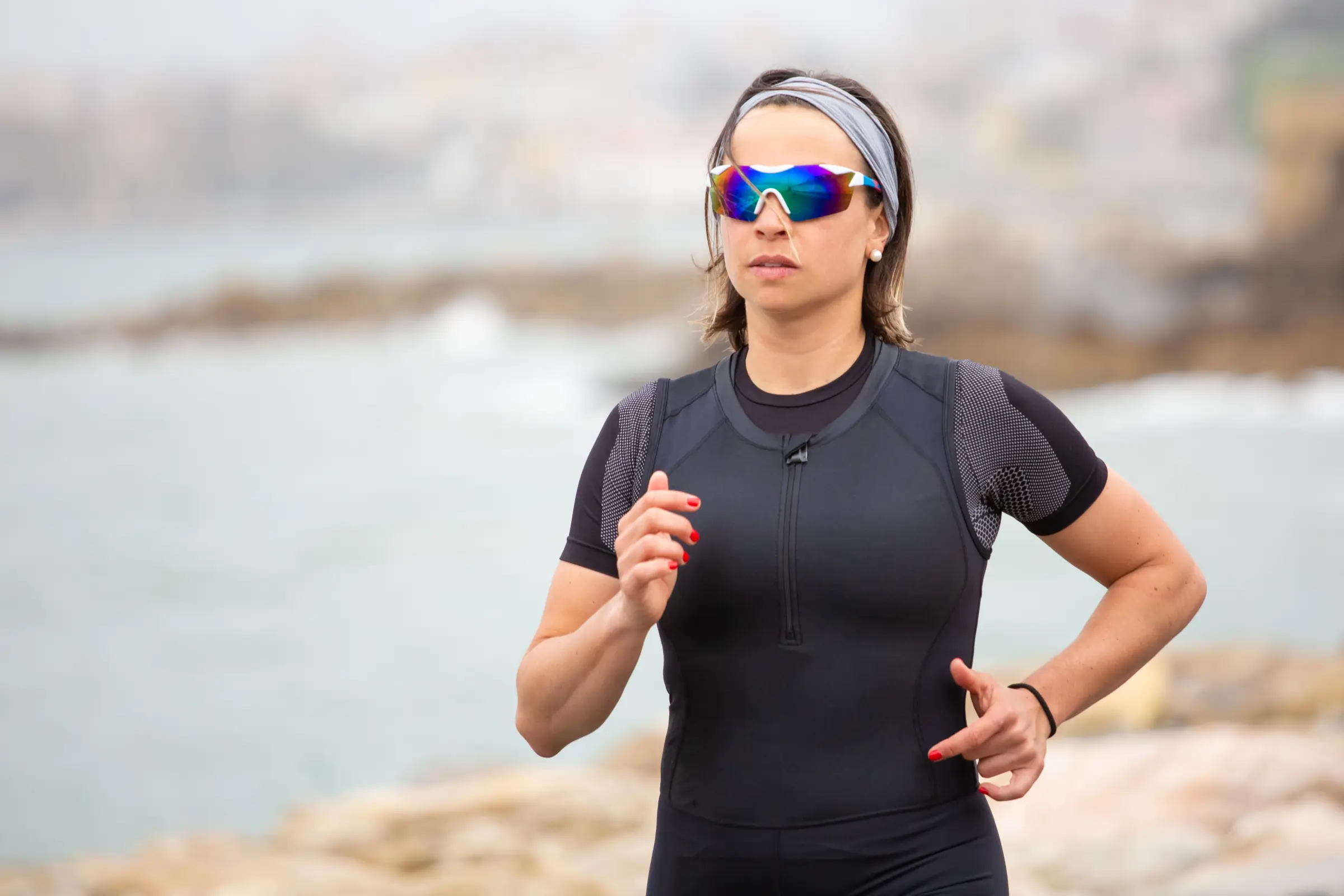 Laufende Sportlerin an der Küste Läuferin mit Sportbrille beim Joggen – Sportbrille für optimale Sicht, UV-Schutz und Komfort beim Outdoor-Sport.