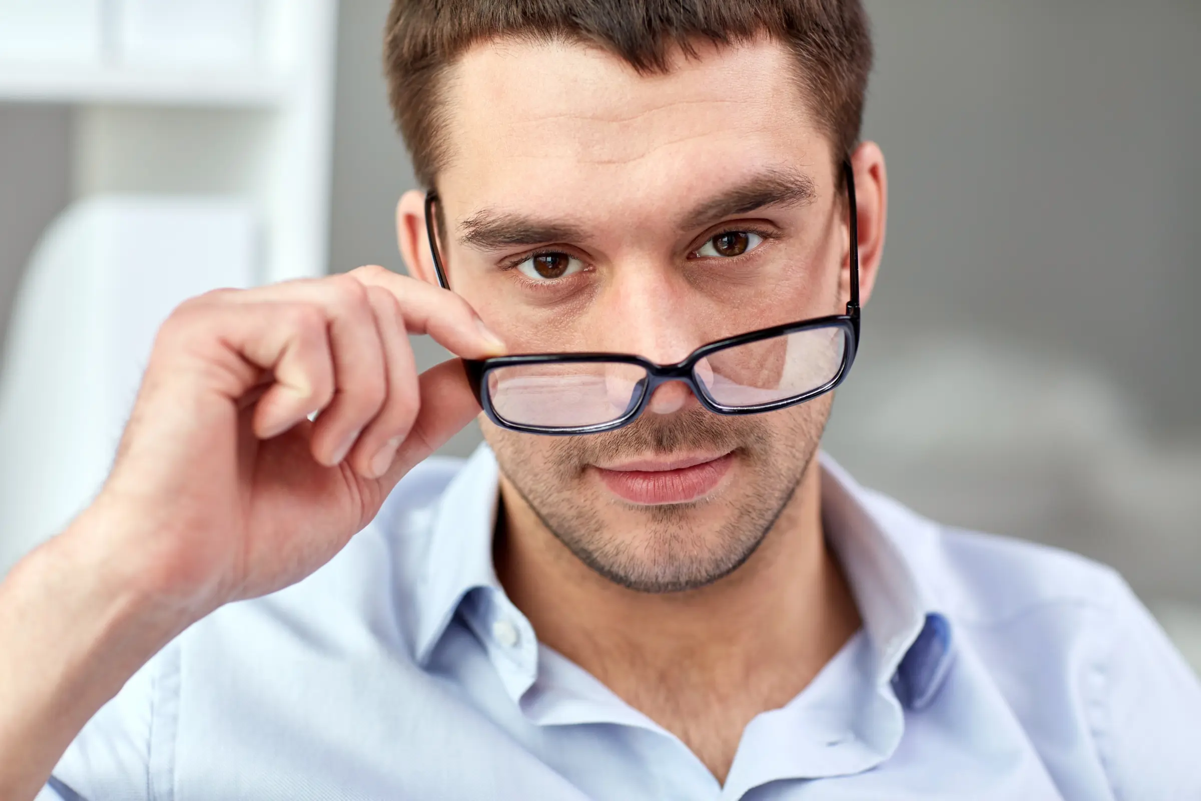 Mann nimmt seine Brille herunter und schaut über die Brillengläser